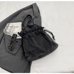 Detail of dark grey denim bucket bag with drawstring closure and adjustable strap