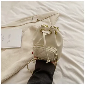Détail du sac seau matelassé crème avec chaîne dorée et cordon de serrage en cuir