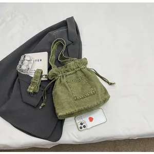 Detail of vintage green denim drawstring bucket bag with adjustable crossbody strap