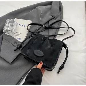 Detail of black matte leather shoulder bag with drawstring knots and mico & she branding
