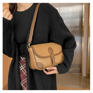 Close-up of brown textured leather saddle bag with contrast trim and gold buckle detail