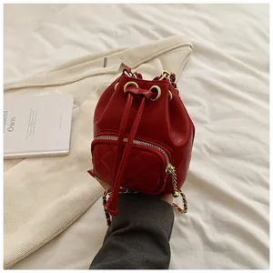 Détail du sac seau en cuir rouge matelassé avec bandoulière chaîne dorée et cordon de serrage