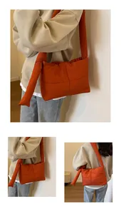 Close-up of orange quilted padded shoulder bag featuring decorative side knot detail