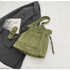 Detail view of olive green denim bucket bag with drawstring and adjustable shoulder strap