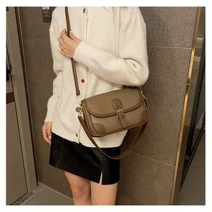 Detail of vintage brown crossbody bag with lychee texture and metallic buckle accent