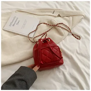 Détail du sac seau rouge matelassé avec cordon de serrage et bandoulière chaîne dorée