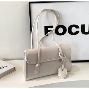 Detail view of the cream minimalist baguette bag featuring dual thin straps and magnetic flap