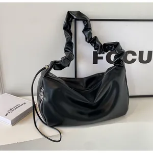 Detail of black hobo bag with pleated shoulder strap and silver zipper pendant