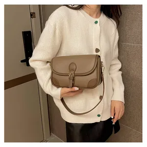 Brown leather shoulder bag with lychee texture and gold buckle shown on a model