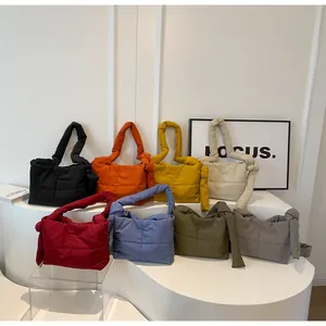 Detailed group view showing various colors of quilted puffer handbags with knotted straps