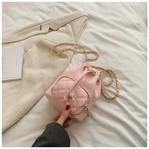Détail du sac seau matelassé rose avec chaîne dorée et fermeture à cordon