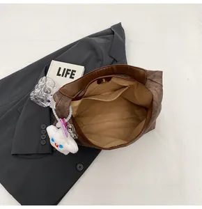 Detailed interior of a brown textured tote bag with zipper pocket and cloud charm
