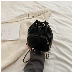 Gros plan du sac seau noir matelassé avec bandoulière chaîne dorée et cordon de serrage