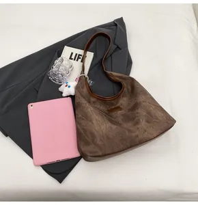 Detail of dark brown suede hobo bag with leather label and white cloud plush charm