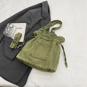 Olive green denim drawstring bucket bag with adjustable strap and front pocket