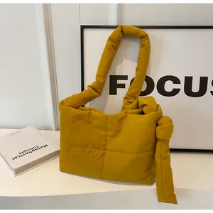 Detail of yellow quilted puffer shoulder bag featuring unique knotted strap design