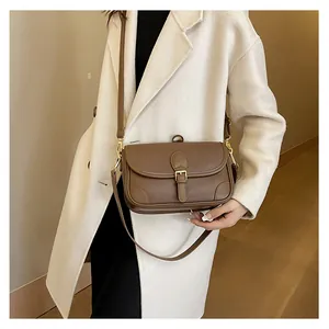 Close-up of brown pebbled leather texture and gold metal clasp on a flap crossbody bag