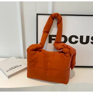 Detail of orange quilted crossbody bag with puff texture and soft nylon fabric finish