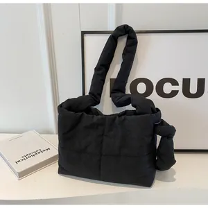 Detail view of black quilted puffer bag with large knot on the shoulder strap