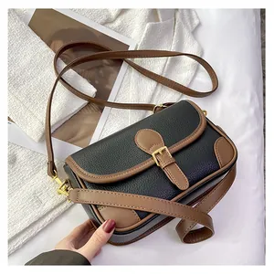 Close-up of black lychee grain leather underarm bag with brown trim and gold buckle detail
