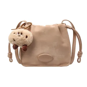 Beige pleated drawstring bucket bag with knot strap detail and plush bear charm
