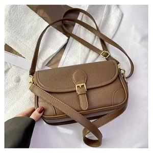 Detail of vintage brown lychee leather crossbody bag with gold buckle and adjustable strap