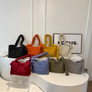 Minimalist quilted puffer tote bags with knotted handles in various colors displayed on white stand