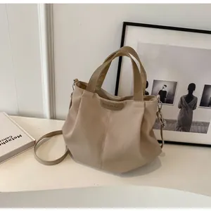 Detail of beige pleated canvas tote bag featuring BUDBAO embossed leather tag and dual straps