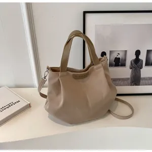 Detail of canvas tote bag with leather handles and detachable metal buckle shoulder strap