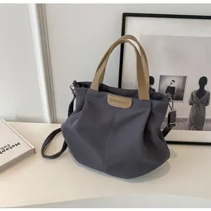 Detail of dark grey canvas tote bag showing brand patch and adjustable shoulder strap