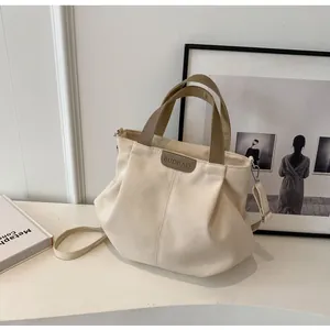 Detail of large capacity canvas tote bag with contrast handles and leather brand patch