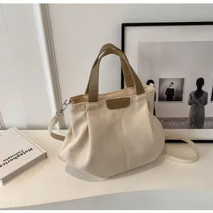 Detail of canvas tote bag with vertical pleats and dark brown leather accents