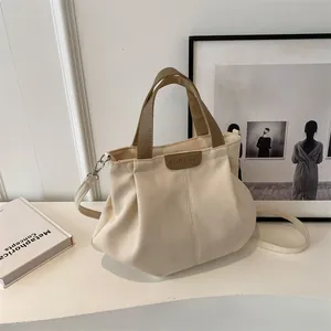 Minimalist off-white large canvas tote bag with brown handles and a detachable shoulder strap