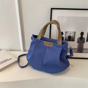 Navy blue large capacity canvas tote bag with khaki straps shown on a desk