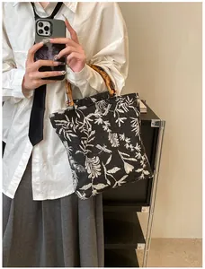 Close-up of jacquard canvas handbag featuring natural bamboo handle and leaf patterns