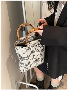 Detail of a beige floral canvas tote bag featuring a vintage natural bamboo top handle