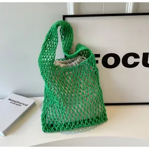 Detail of green woven tote bag showing the hollow mesh texture and canvas drawstring liner