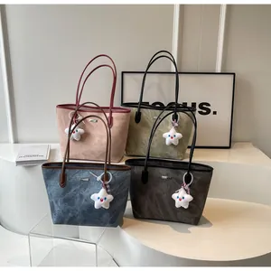 Dettaglio di quattro borse tote nei colori rosa, oliva, blu e antracite con ciondoli a stella