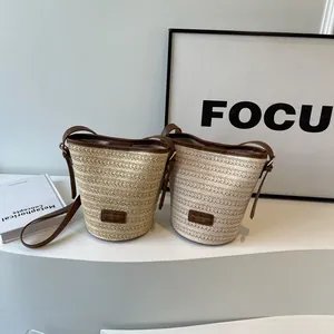 Handcrafted straw bucket bag with brown leather trim and long crossbody shoulder strap