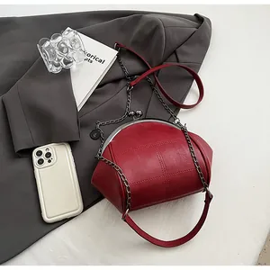 Dettaglio borsa a conchiglia rossa trapuntata con chiusura vintage e tracolla a catena