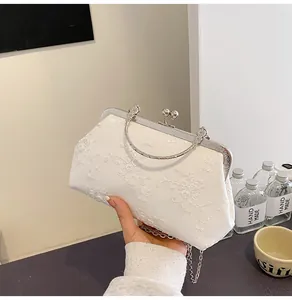 Dettaglio del pizzo floreale bianco e chiusura in metallo argentato della borsa da sera