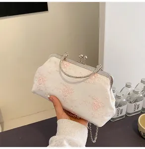 Dettaglio elegante pochette da sera in raso bianco con ricamo floreale rosa e catena