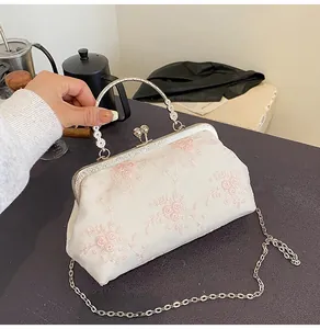 Dettaglio della borsa vintage con ricami floreali ed elegante manico in metallo