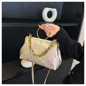 Detail view of champagne gold geometric embossed handbag with ring handle and gold chain