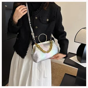 Detail of silver iridescent crossbody bag with chain strap and round golden handle