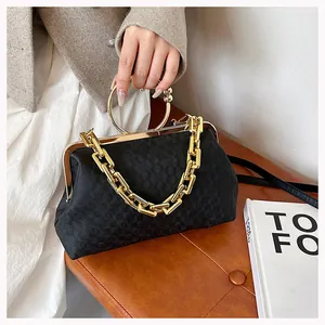 Close-up of black retro textured handbag with round gold handles and chain strap