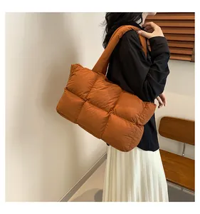 Detail of quilted bright orange tote bag with padded soft texture and wide shoulder strap