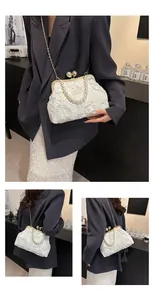 Detailed view of white floral embroidery bag with large pearl clasp and pearl handle