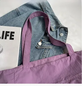 Detail showing reinforced stitching and durable nylon handles of the purple tote bag