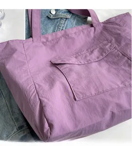 Detail of purple nylon tote bag featuring front pocket on denim jacket background